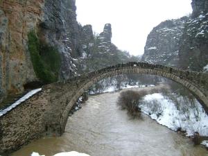 un puente de piedra sobre un río en la nieve en Xenonas Zagorisio, en Tsepelovo