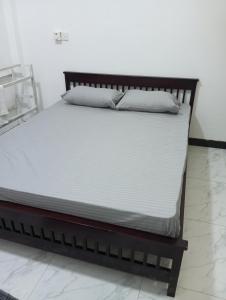 a bed with white sheets and pillows on it at Anne's Homestay in Gampaha