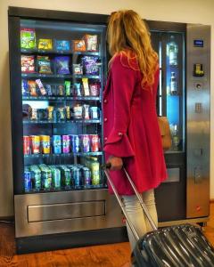 Uma mulher a passar a bagagem por uma máquina de refrigerantes. em motel isar | 24h/7 checkin em Pilsting