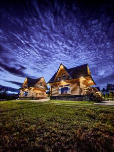 a large wooden house with a sky at night at Domki Na Grapie - z widokiem na Tatry in PyzÃ³wka
