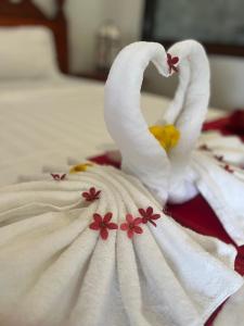 a white towel with flowers on a bed at Villa Namkhan Heritage in Luang Prabang