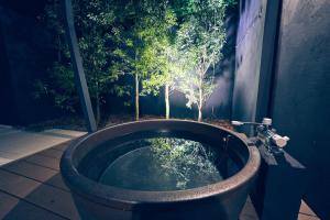 une baignoire en pierre avec une fontaine dans le jardin dans l'établissement ルクス箱根湯本 LUX HAKONE YUMOTO, à Hakone