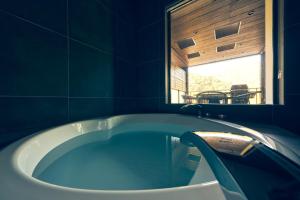 een badkamer met een bad en een raam bij ルクス箱根湯本 LUX HAKONE YUMOTO in Hakone