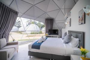 a bedroom with a bed and a large window at Athena Glamping Khaoyai in Pak Chong
