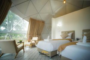 a bedroom with two beds and a chair and a window at Athena Glamping Khaoyai in Pak Chong