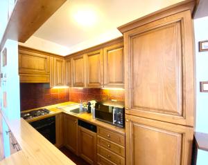cocina con armarios de madera, fregadero y microondas en FALORIA APARTMENT en Cortina dʼAmpezzo