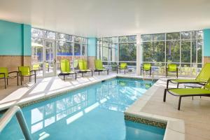 a pool with green chairs and tables in a building at SpringHill Suites by Marriott Frederica in Frederica