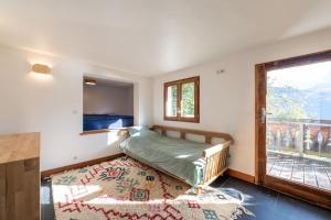1 dormitorio con cama, ventana y alfombra en Le Relief - Maison avec magnifique vue montagne aux Bettex, en Saint-Gervais-les-Bains