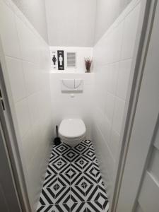 baño con aseo y suelo de baldosa blanco y negro. en Apartament Widok, en Świebodzin