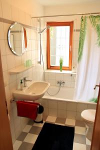 ein Badezimmer mit einem Waschbecken, einer Badewanne und einem Spiegel in der Unterkunft Catalena in Radolfzell am Bodensee