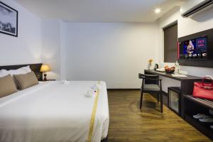 a bedroom with a bed and a desk with a television at La Sera Hotel in Nha Trang