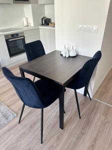 uma mesa de jantar preta com 2 cadeiras azuis em Apartmán s balkónom pri letisku na skok do centra mesta em Bratislava