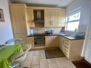 a kitchen with wooden cabinets and a sink and a window at Ballycastle Modern Town House in Ballycastle