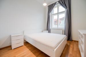 a white bedroom with a bed and a window at Hotel U 3 Pstrosu in Prague