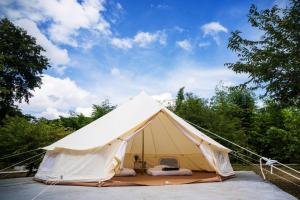 a large white tent in a field with trees at Athena Glamping Khaoyai in Pak Chong