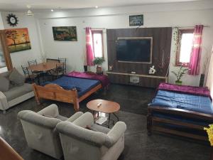 a living room with a couch and a tv at Ratnagiri Homestay in Chikmagalūr