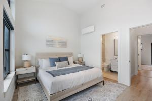 biała sypialnia z dużym łóżkiem i łazienką w obiekcie Coastal Haven at THE BEACH HOUSE w mieście Campbell River