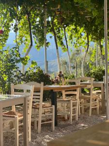 a wooden table and chairs with trees in the background at ELÉA Guesthouse himare in Himare
