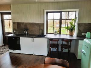 a kitchen with white cabinets and a black counter top at Namelis Gluosnė in Rusnė
