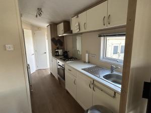 eine Küche mit weißen Schränken und einer Spüle und einem Fenster in der Unterkunft RBR 237 - Beach Resort Kamperland in Kamperland