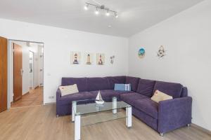 ein Wohnzimmer mit einem lila Sofa und einem Glastisch in der Unterkunft Baltic Whg 26 in Grömitz