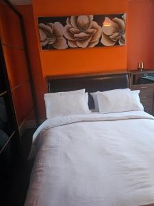 1 dormitorio con cama blanca y pared de color naranja en The Margaret Residence en Bexhill