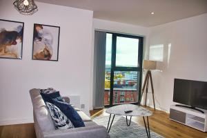 a living room with a couch and a flat screen tv at AP- Luxury Apt nxt to o2 Academy in Birmingham