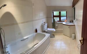 a bathroom with a tub and a toilet and a sink at The Byre, at Cradle Barn offering a king suite in Abingdon
