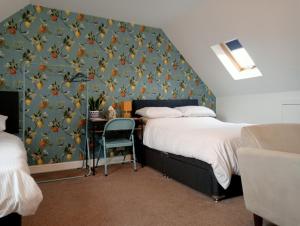 ein Zimmer mit zwei Betten und einem Schreibtisch mit einer Wand in der Unterkunft Hill View Studio in Hawick