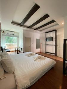 een groot wit bed in een kamer met een tafel bij เดอะวิลล่า71 รีสอร์ท in Ban Zong Katiam