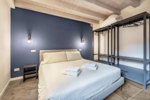 1 dormitorio azul con 1 cama con 2 toallas en La Casa Incartata - Carta da Zucchero, en Toscolano Maderno