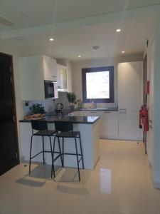 a kitchen with a counter and two stools in it at Sunrise Sifah in As Sīfah