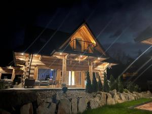a log home at night with the lights on at LITTLE KOIS VILLAGE in Dzianisz