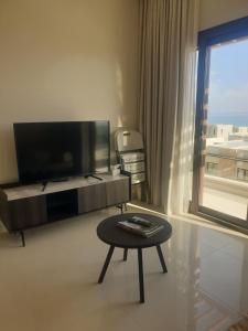 a living room with a flat screen tv and a table at Peace in Sifah -Sea view in As Sīfah