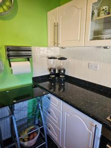 a kitchen with white cabinets and green walls at The Margaret Residence in Bexhill