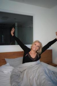 una mujer acostada en una cama con sus brazos en el aire en motel isar | 24h/7 checkin en Pilsting