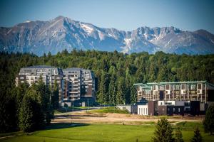 a largeartment building with mountains in the background at Harmony Apartment in Silver Mountain in Poiana Brasov