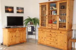 a wooden entertainment center with a television and a wooden hutch at Fewo Peeneblick 5_LIND in Ostseebad Karlshagen
