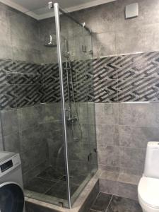 La salle de bains est pourvue d'une douche avec une porte en verre. dans l'établissement Двухкомнатная квартира в центре города, à Uralsk