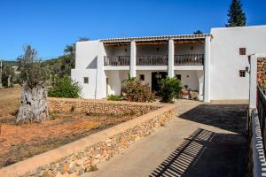 Casa blanca con pared de piedra y edificio en New! Villa Na Ribes, en Sant Carles de Peralta