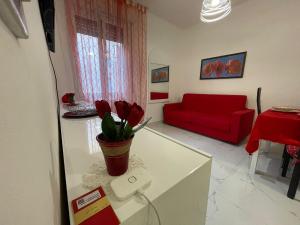 a living room with a red couch and a table at Dolce Vita A 5 Minuti Dal Centro Con Parcheggio Privato Gratuito in Sanremo