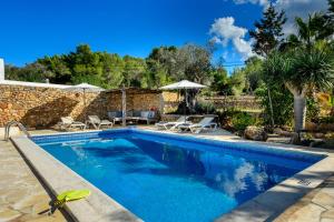 una piscina en un patio con sillas y sombrillas en New! Villa Na Ribes, en Sant Carles de Peralta