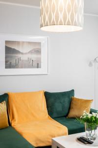 a living room with a green couch and a chandelier at Apartment Floriana Stablewskiego Poznań by Renters in Poznań