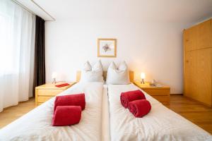 ein Schlafzimmer mit zwei roten Kissen auf einem weißen Bett in der Unterkunft Chasa Plavna in Vulpera