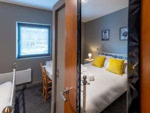 Un dormitorio con una cama con almohadas amarillas y una mesa. en Pass the Keys Modern flat a short walk from Shrewsbury centre, en Shrewsbury