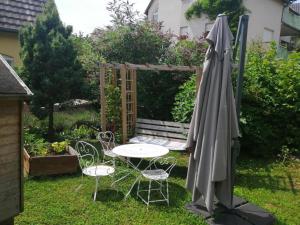 una mesa y sillas en un jardín con sombrilla en Chez Olivier and Josette in Mulhouse Sud, en Illfurth
