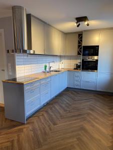 a large kitchen with blue cabinets and a wooden floor at Enter Tromsø - Luxury 4 Bedroom Apartment in Tromsø