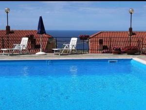 a blue swimming pool with two chairs and a building at Bel Tramonto - Appartamento vista mare in Ospedaletti