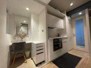 a kitchen with white cabinets and a chair and a window at Modern self-contained Ground and Basement studios in London