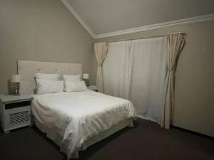 een slaapkamer met een wit bed en een raam bij Executive suite@Lofts in Pretoria